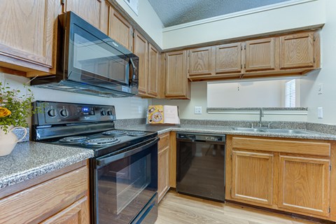 A kitchen with wooden cabinets and black appliances.